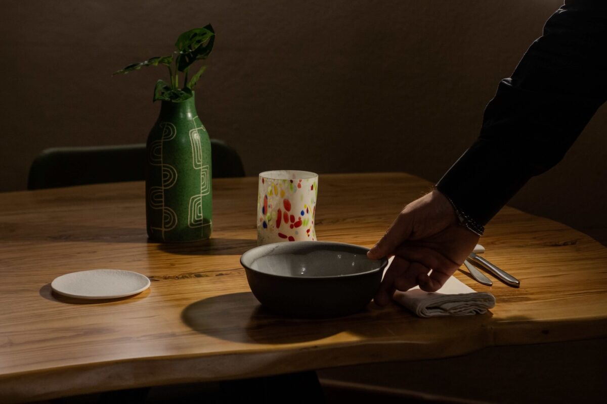 Cameriere che serve un piatto gourmet con un calice di vino al ristorante San Bernardo, situato a Calci, Pisa. Atmosfera elegante e servizio raffinato in un ristorante toscano